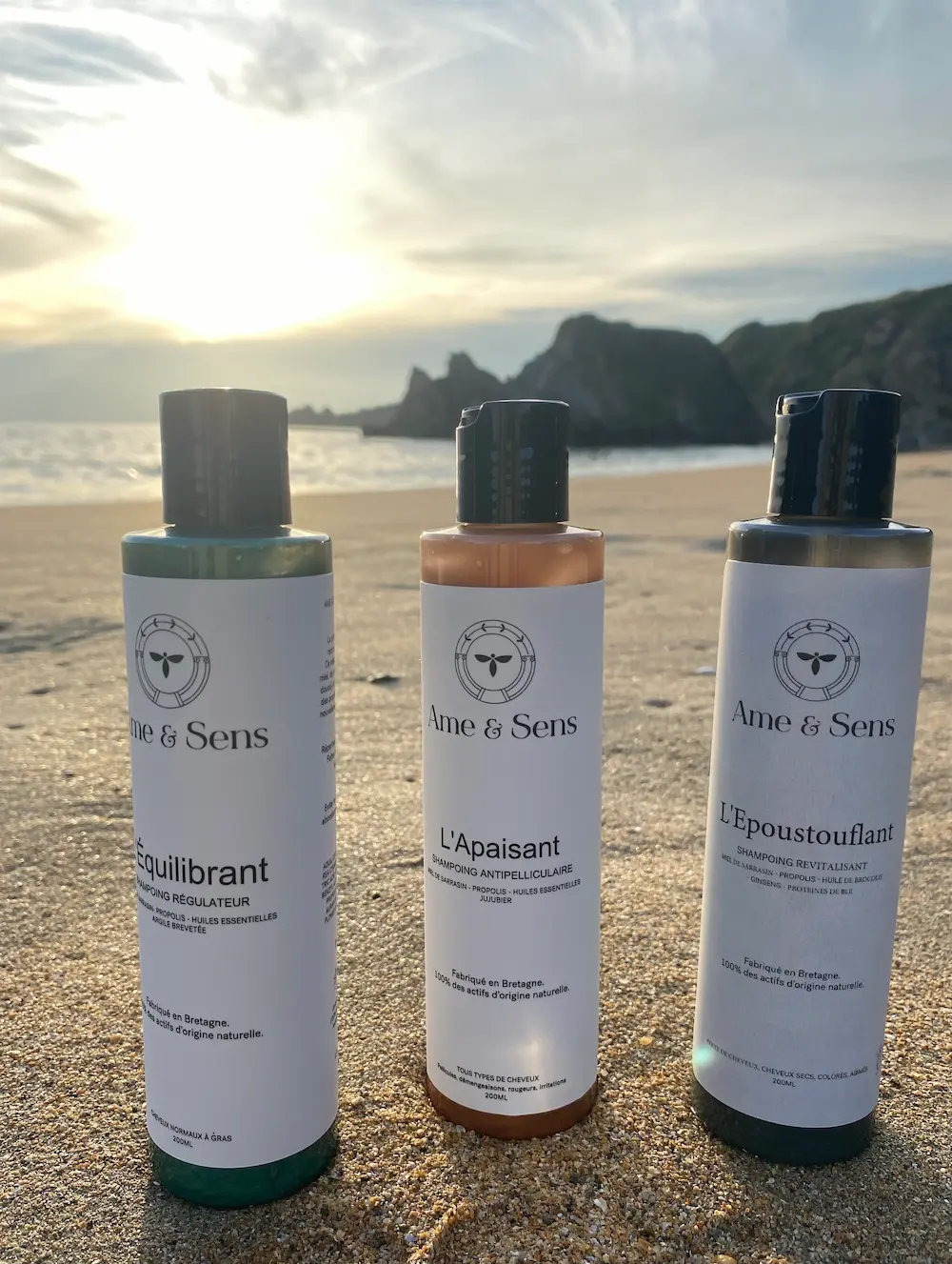 Gamme de shampoings traitants Âme et Sens sur une plage de Bretagne